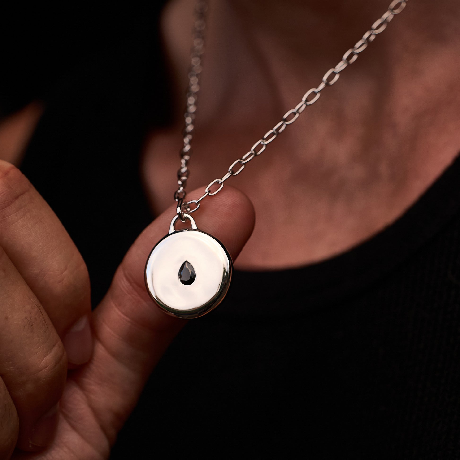 Close-up of a person wearing the Teardrop Pendant, featuring a black cubic zirconia stone set in rhodium-plated sterling silver, on a 52cm sterling silver chain.