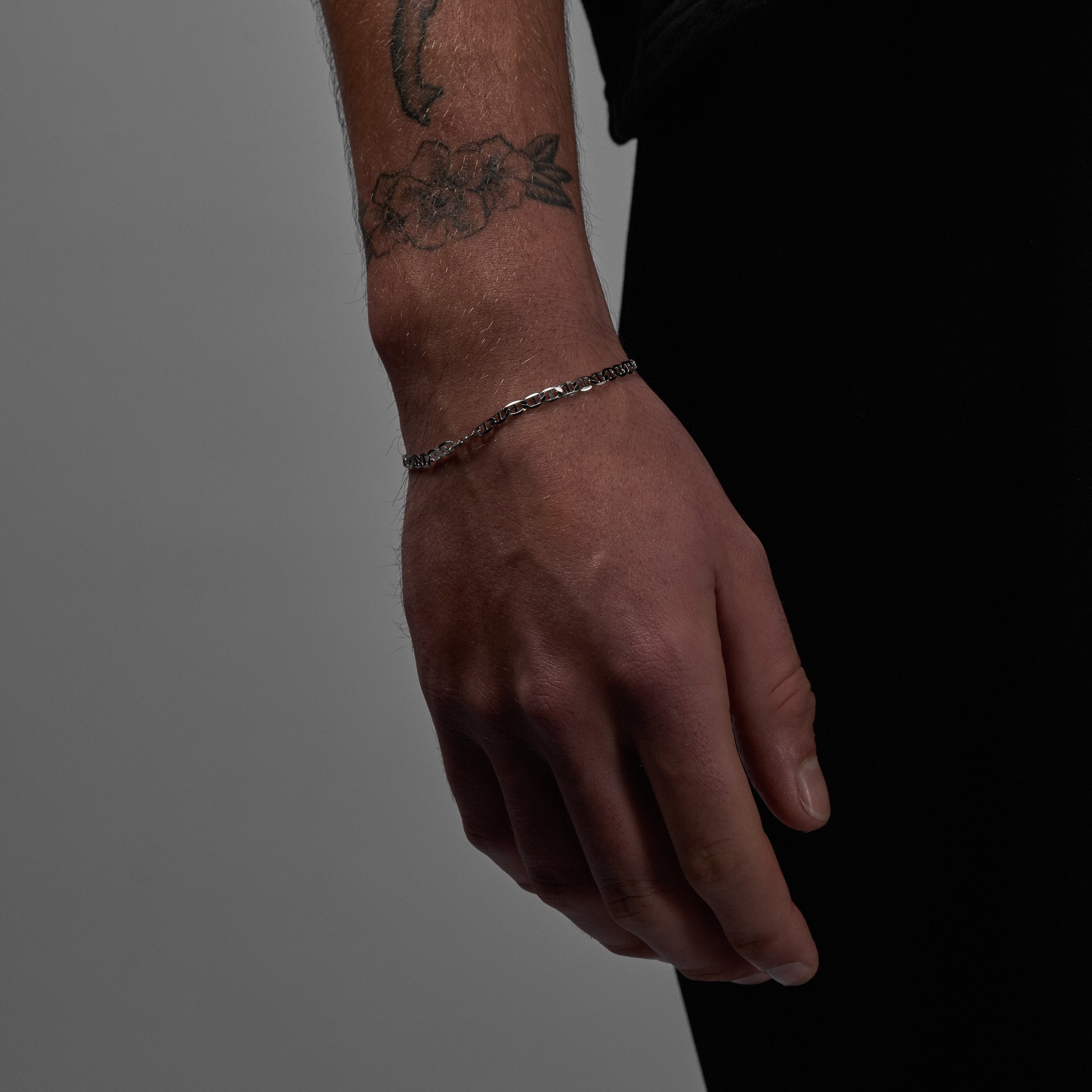 A man wearing and showcasing silver Infinite Bracelet close up