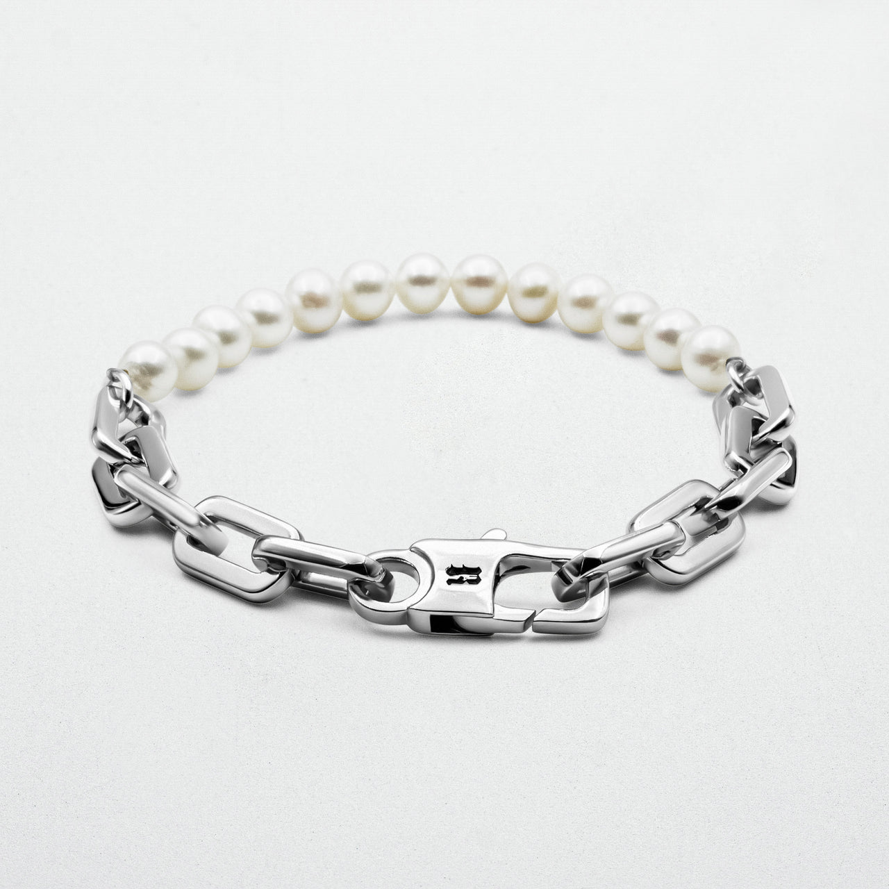 Axel Pearl Bracelet featuring smooth freshwater pearls and high-polish rhodium-plated recycled sterling silver, secured with a robust clasp and signature logo.